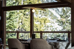A dining table set with wine glasses and a pitcher, positioned near a window with a view of trees. - Penthouse in Courchevel Moriond, Belvédère area (Courchevel)