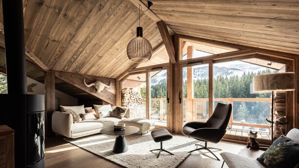 A spacious living room with a wooden ceiling, large windows offering mountain views, a sofa, a coffee table, and a fireplace. - Penthouse in Courchevel Moriond, Belvédère area (Courchevel)