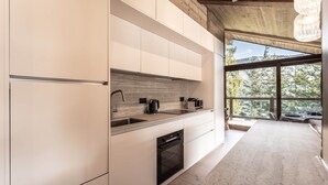 A modern kitchen with white cabinetry, a built-in oven, and a large window offering a view of trees. - Penthouse in Courchevel Moriond, Belvédère area (Courchevel)