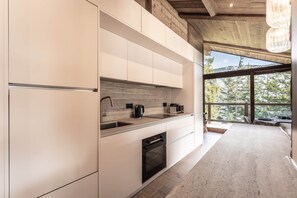 A modern kitchen with white cabinetry, a built-in oven, and a large window offering a view of trees. - Penthouse in Courchevel Moriond, Belvédère area (Courchevel)
