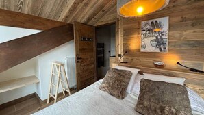 A bedroom with a wooden ceiling, a bed with two pillows, a ladder, and a radiator. - Penthouse in Courchevel Moriond, Belvédère area (Courchevel)
