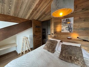 A bedroom with a wooden ceiling, a bed with two pillows, a ladder, and a radiator. - Penthouse in Courchevel Moriond, Belvédère area (Courchevel)
