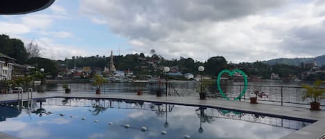 A swimming pool with a view of a town and hills in the background.