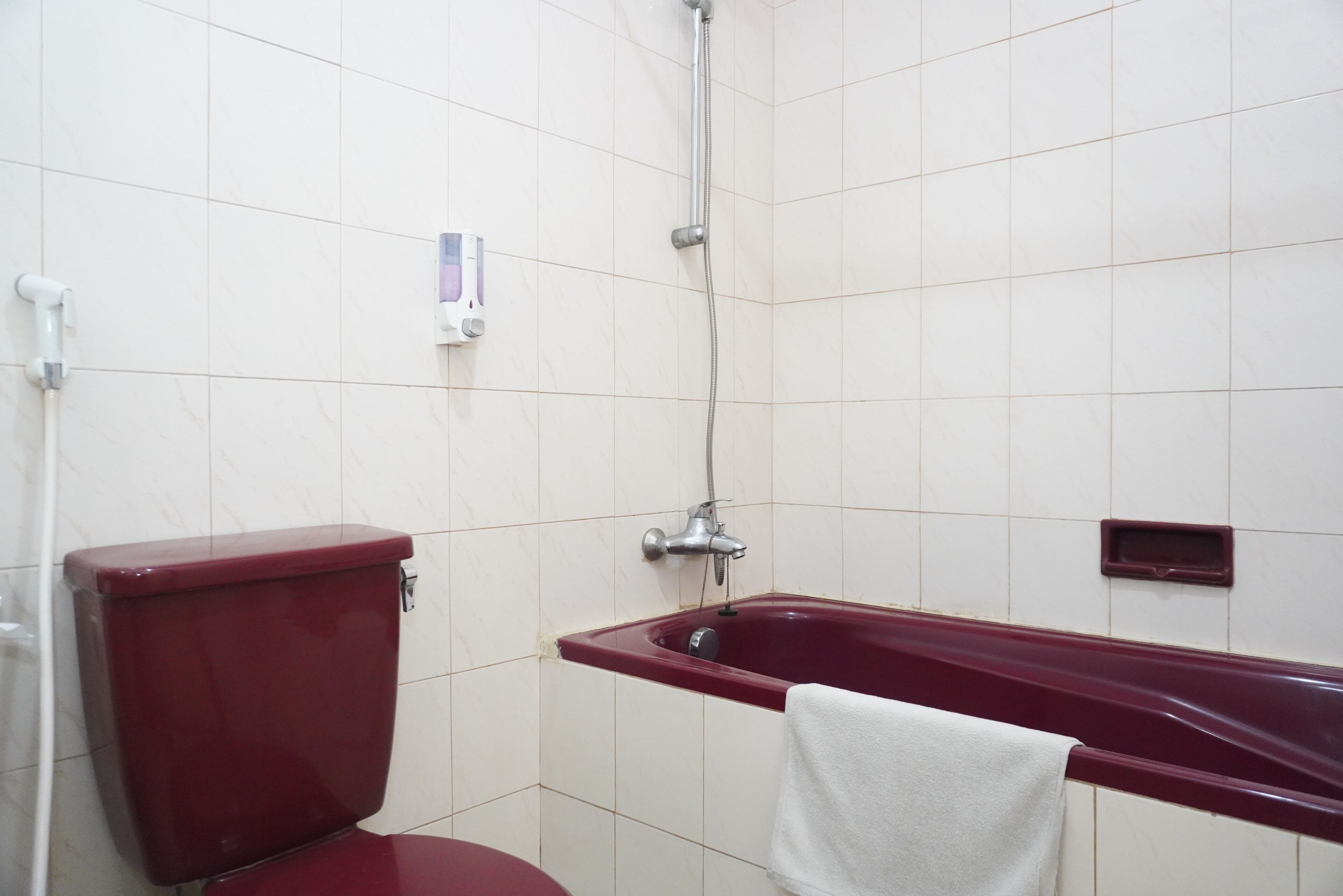 A bathroom with a red toilet, a bathtub, and a shower.