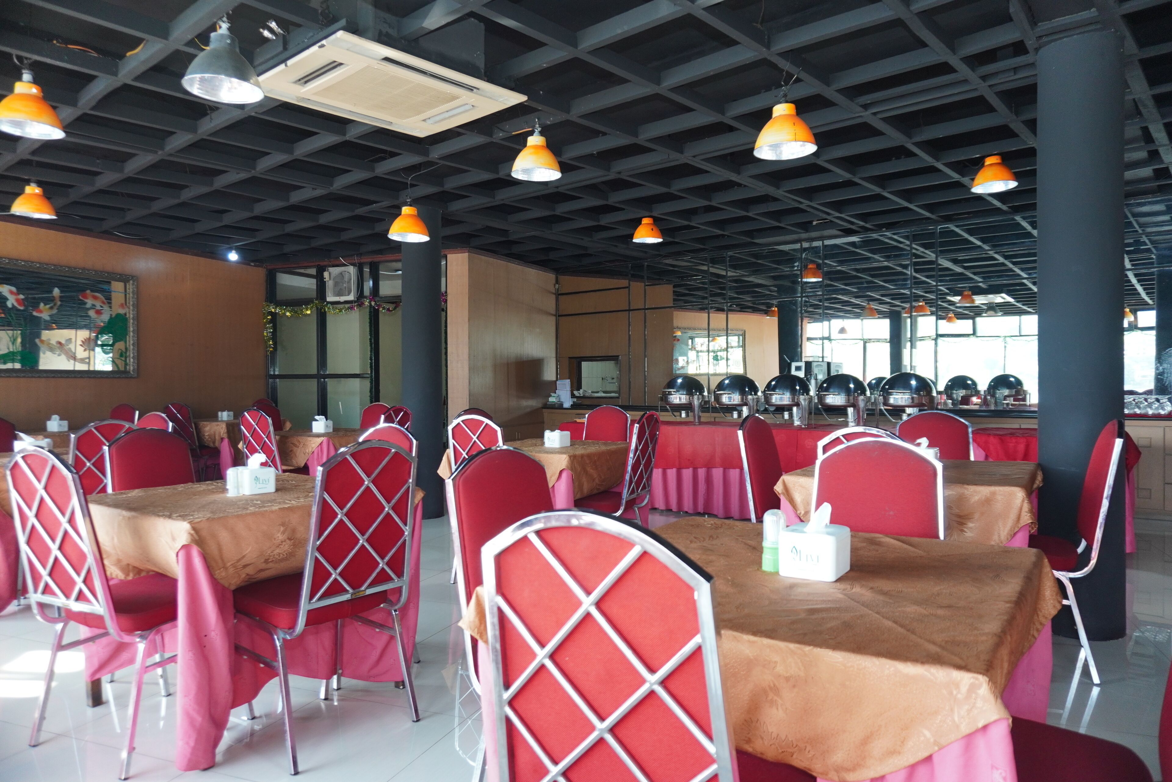 Un comedor con mesas, sillas, unidades de aire acondicionado y lámparas colgantes.