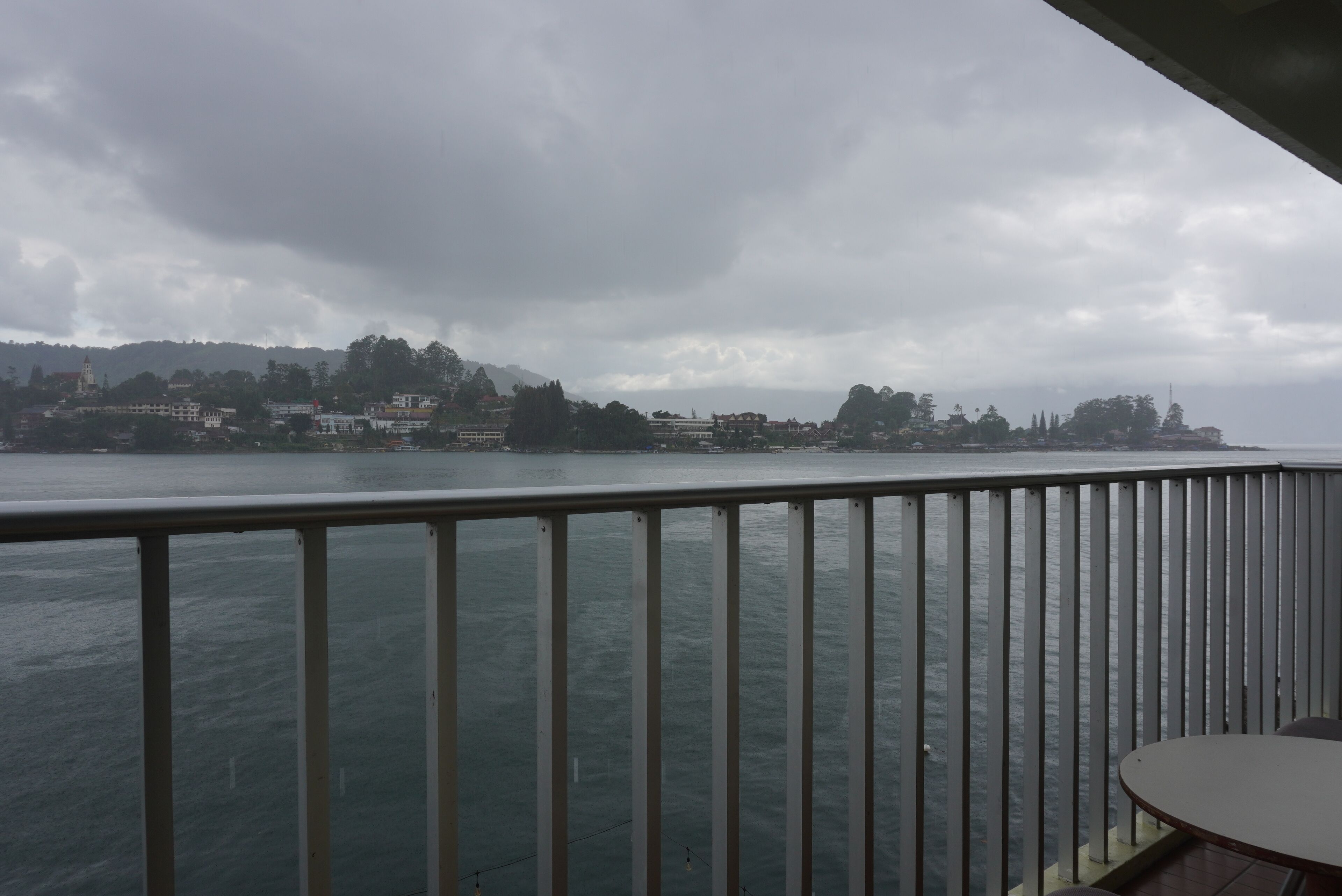 A view from a balcony overlooking a body of water with buildings in the distance.