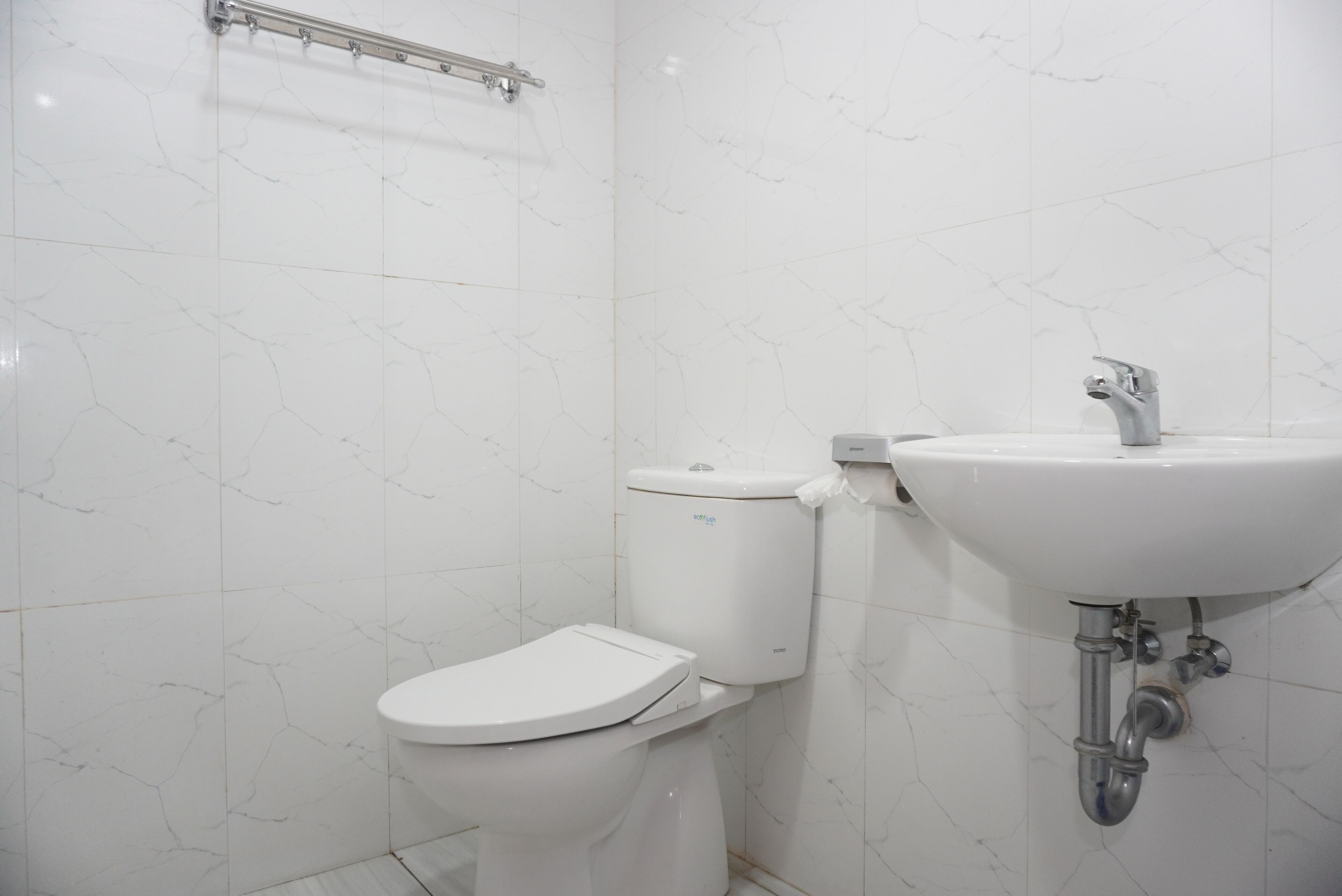 A bathroom with a toilet, sink, and a towel rack.