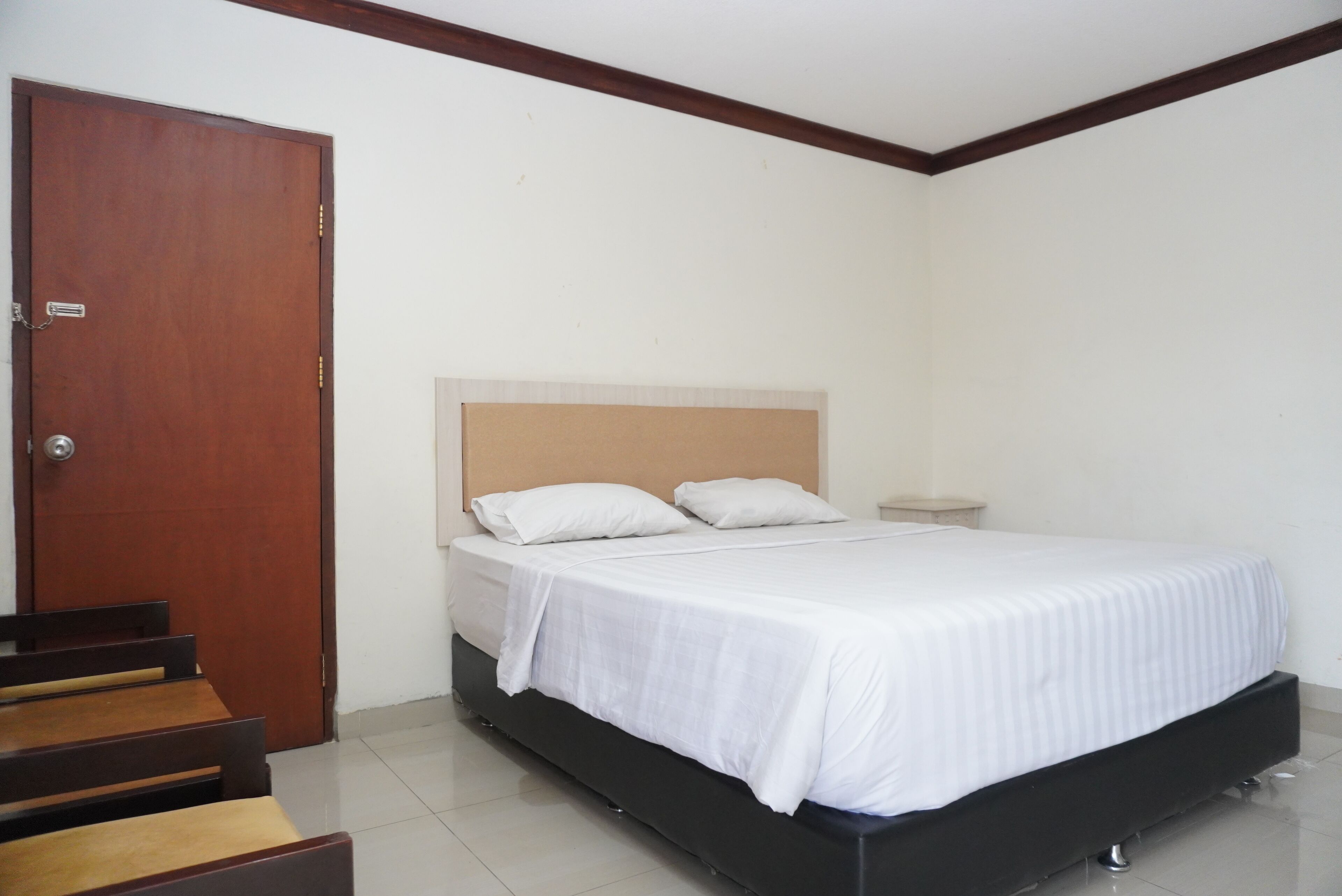 A bedroom with a bed, a wooden door, and a small bedside table.