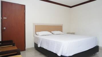 A bedroom with a bed, a wooden door, and a small bedside table.