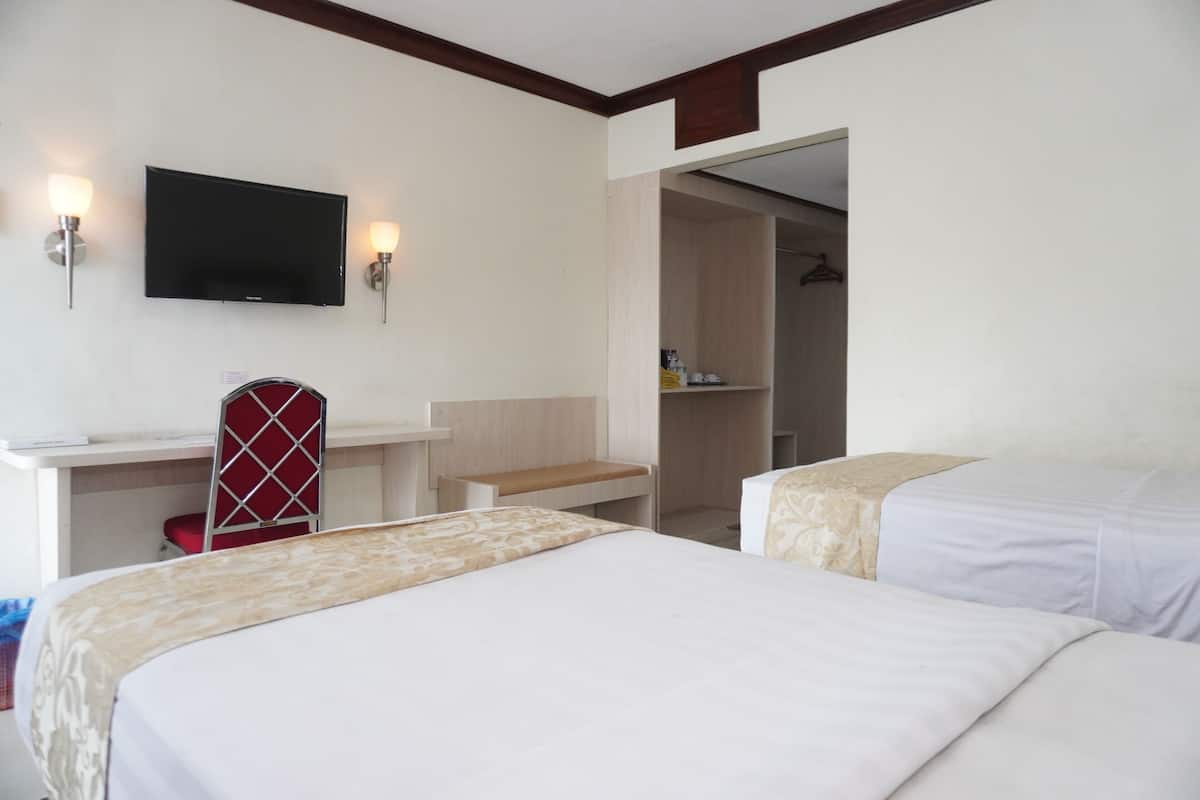 A hotel room with two beds, a desk, a chair, a TV, and a wardrobe.