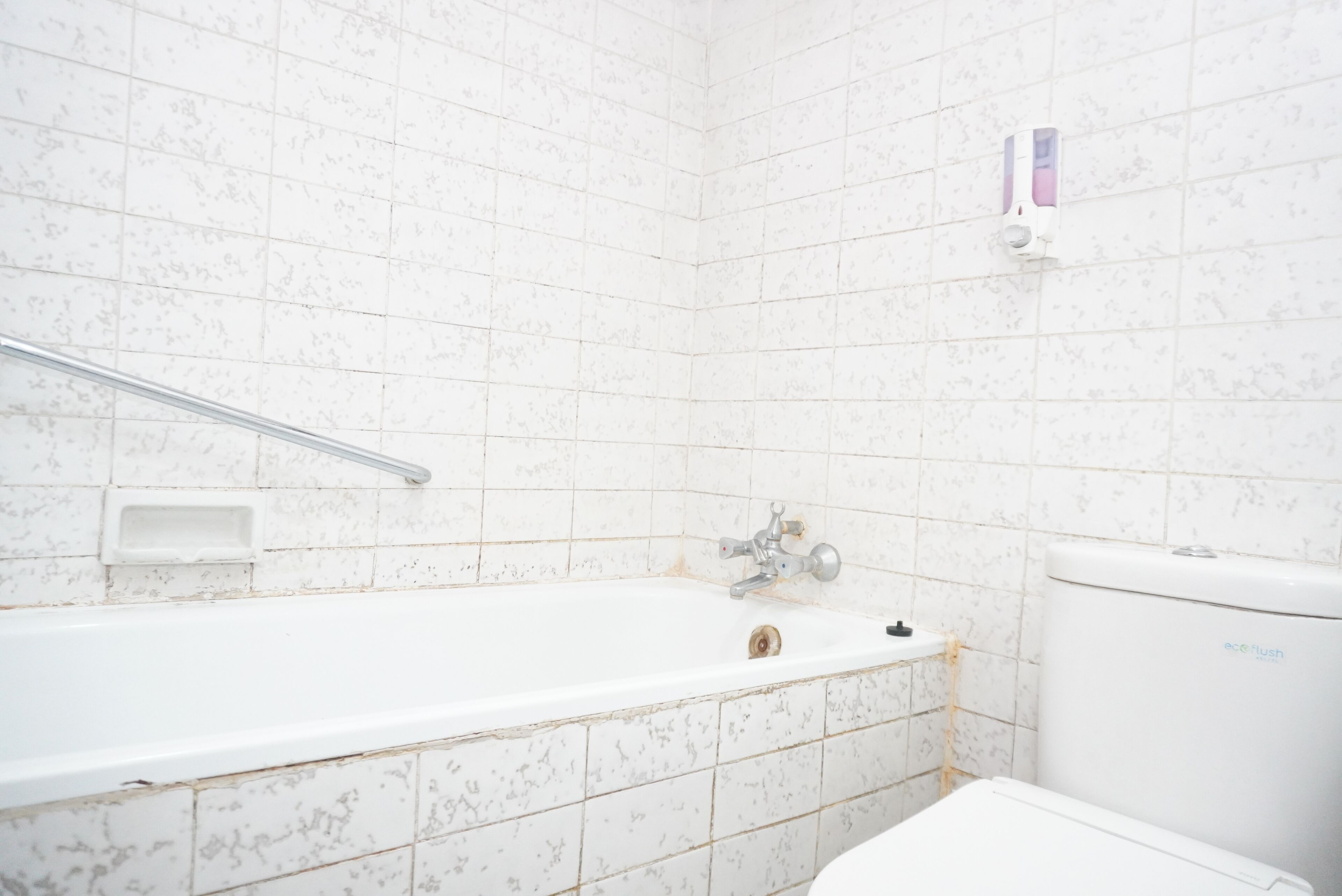 Un baño con bañera, inodoro y un secador de manos en la pared.