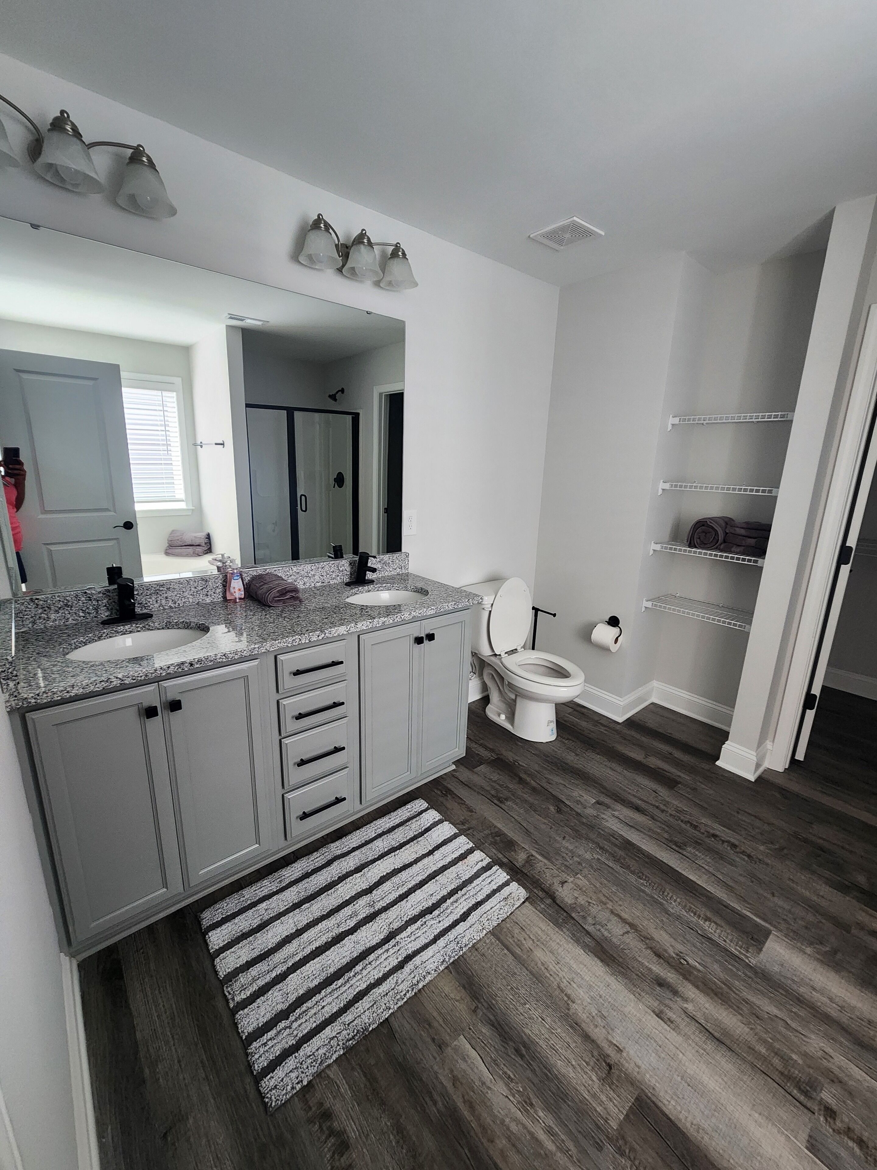A bathroom with a granite countertop, a toilet, and a shower area.