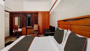 Une chambre d’hôtel avec un grand lit, un bureau, une chaise et une armoire.