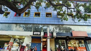 Un hôtel à la façade bleue, une enseigne indiquant « Skyry Hotels », et plusieurs motos garées devant.