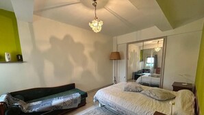 A bedroom with a bed, a sofa, a bedside table, and a lamp.