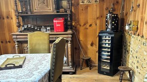 A wooden interior with a table set for dining, a vintage radio, and a refrigerator.