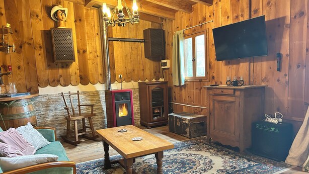 A cozy wooden interior with a fireplace, a television, and rustic decor.