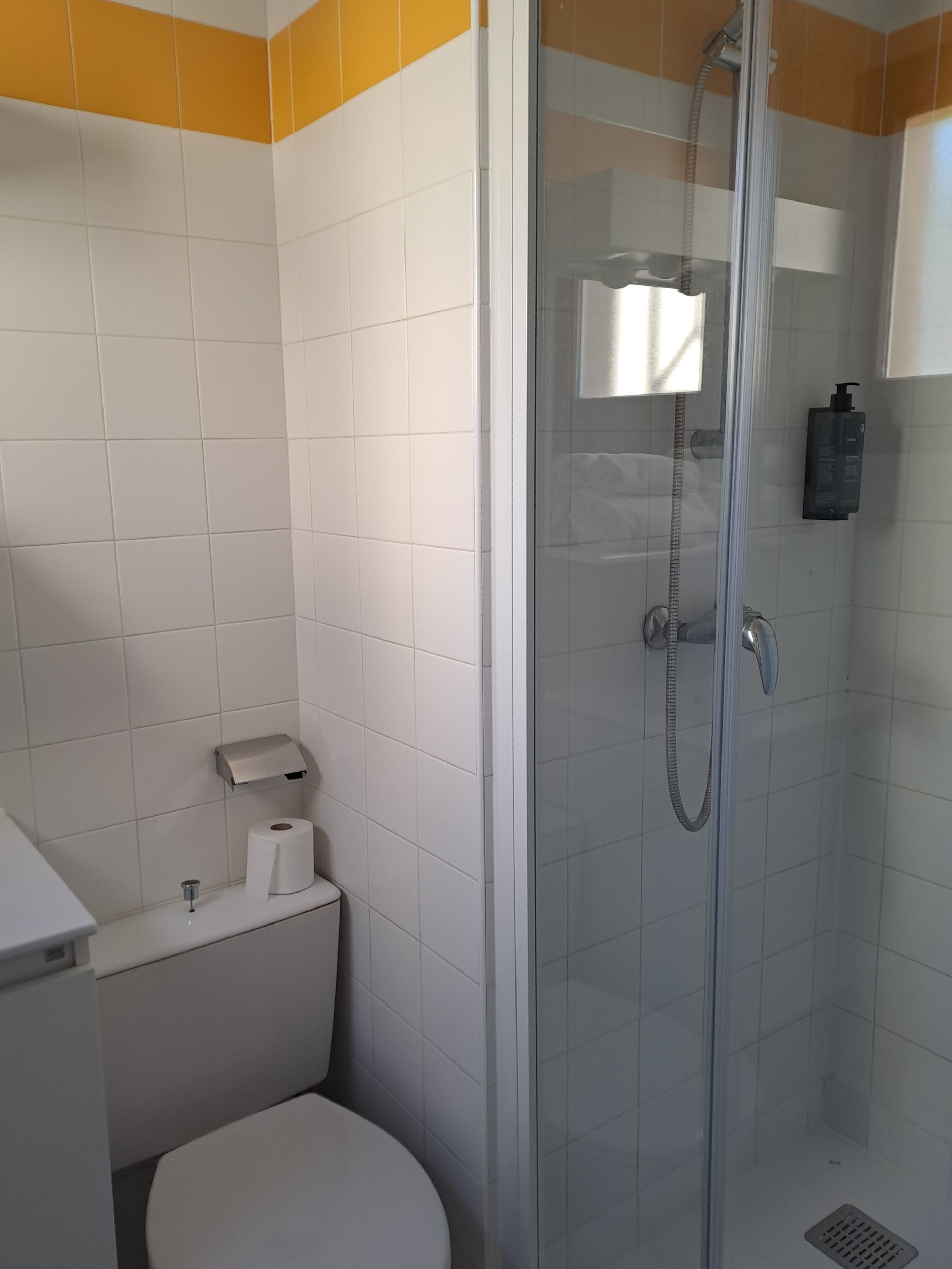 Ein Badezimmer mit Toilette, Duschkabine und einem Händetrockner.