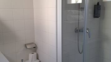 Ein Badezimmer mit Toilette, Duschkabine und einem Händetrockner.