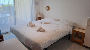 A neatly made bed with towels, a bedside lamp, and a small wooden nightstand. - VVF Hyères presqu'île de Giens (Hyères)