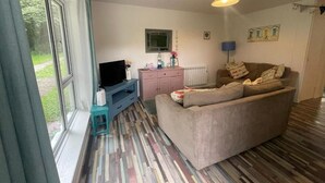 Een woonkamer met een bank, televisie en een raam.