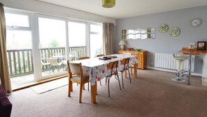 Een eetruimte met een tafel gedekt voor vier personen, een houten kast, een radiator en een raam met uitzicht op het exterieur.