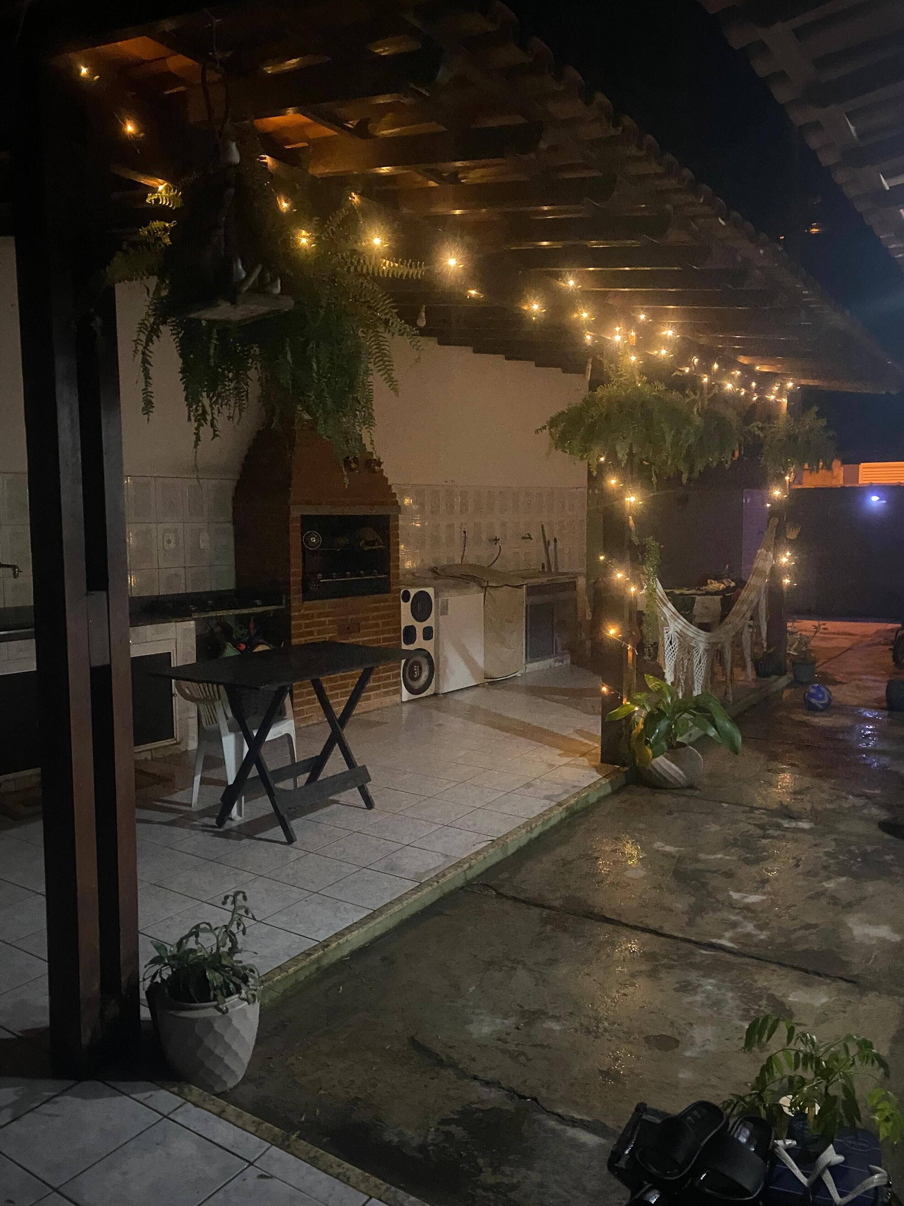 Patio esterno con barbecue, posti a sedere e luci decorative.