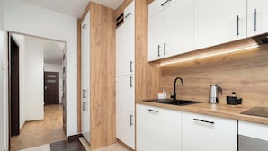 A modern kitchen with white cabinets, a wooden countertop, and a stainless steel sink. - Family Apartment in the Center | 3 Bedrooms and Air Conditioning (Rzeszów)