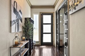 A hallway with a wooden floor, a door with a frosted glass panel, and a wall-mounted light fixture.