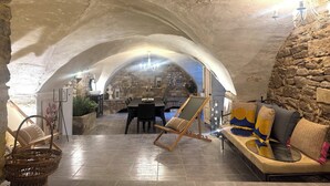 Un interior con arcos de piedra, una zona de comedor y un área de descanso con cojines.