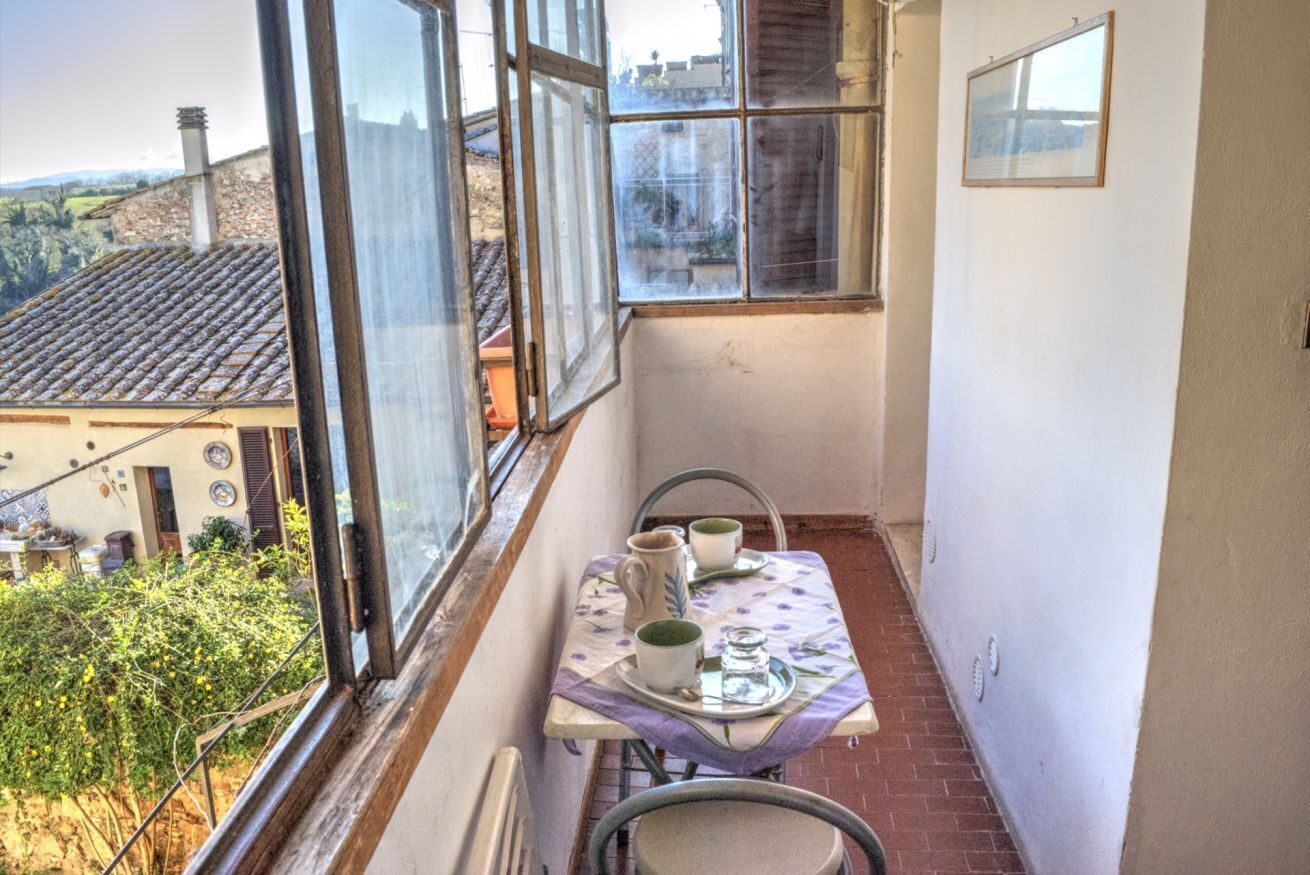 A narrow balcony with a table set for two, overlooking a residential area.