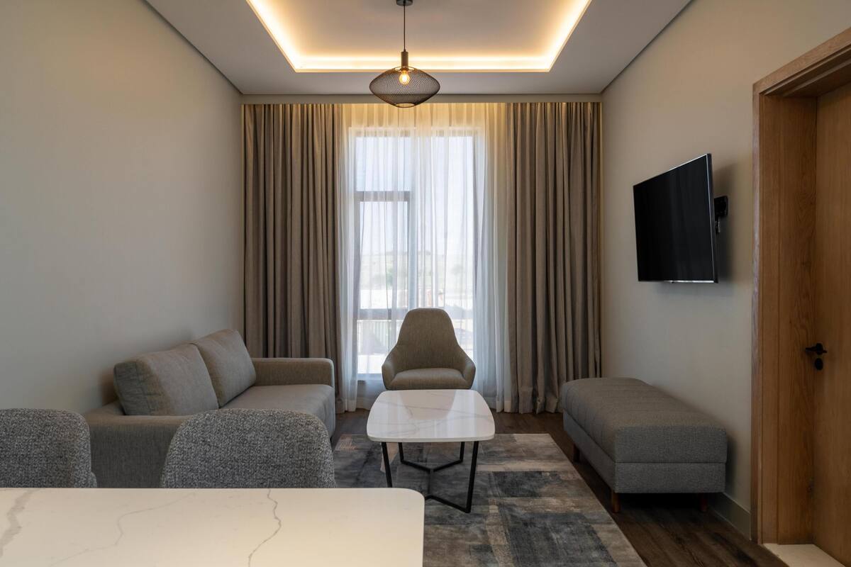 Una sala de estar moderna con un juego de sofá, una mesa de centro y un televisor montado en la pared.