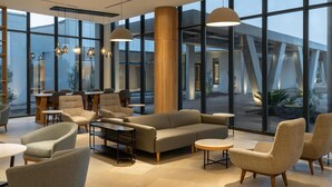 A modern lounge area with seating, large windows, and a central column. - Radisson Hotel And Convention Center Steve Tshwete Middelburg (Middelburg)