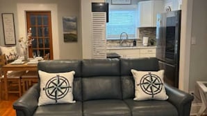 A modern living room with a black leather sofa, two matching pillows, and a wooden coffee table.