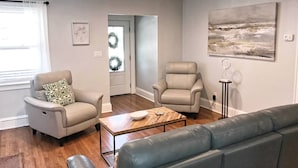 A living room with two beige armchairs, a wooden coffee table, and a grey sofa.