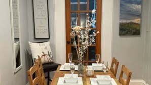 A dining room with a wooden table set for four, flanked by chairs.