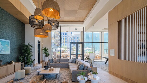 A modern lobby with a large seating area, multiple hanging light fixtures, and large windows offering views of the city. - Saiya  1020 (Phoenix)