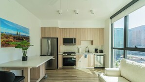 A modern kitchen with wooden cabinets, stainless steel appliances, and a large window offering a city view. - Saiya  1020 (Phoenix)