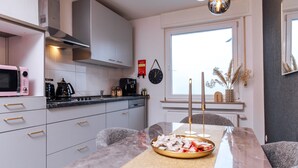 Une cuisine moderne avec des meubles blancs, un plan de travail noir et un coin repas doté d’une table en marbre.