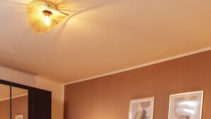 Une chambre à coucher moderne avec un grand lit, des tables de chevet, un miroir et des œuvres d’art encadrées accrochées au mur.