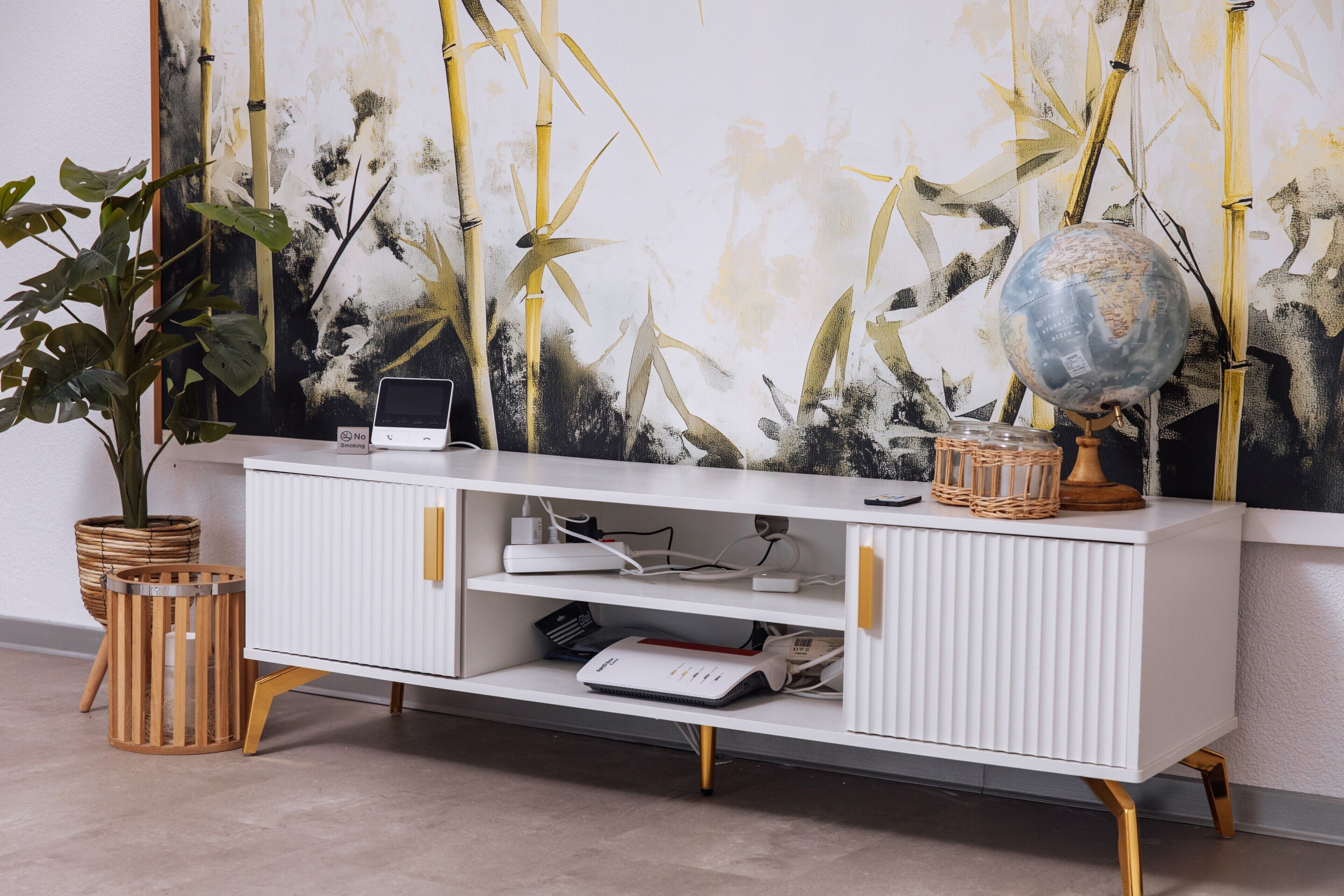 A white cabinet with shelves, a globe, and a laptop on top.