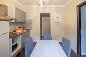 A compact kitchen with a dining table, chairs, and a refrigerator. - BuddyRent - Ghetto - Campo de' Fiori - 6 ospiti (Roma)