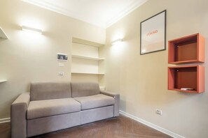 A living room with a sofa, built-in shelves, and a framed picture on the wall. - BuddyRent - Ghetto - Campo de' Fiori - 6 ospiti (Roma)