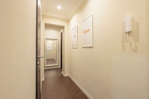A hallway with a door, a phone, and two framed signs on the wall. - BuddyRent - Ghetto - Campo de' Fiori - 6 ospiti (Roma)