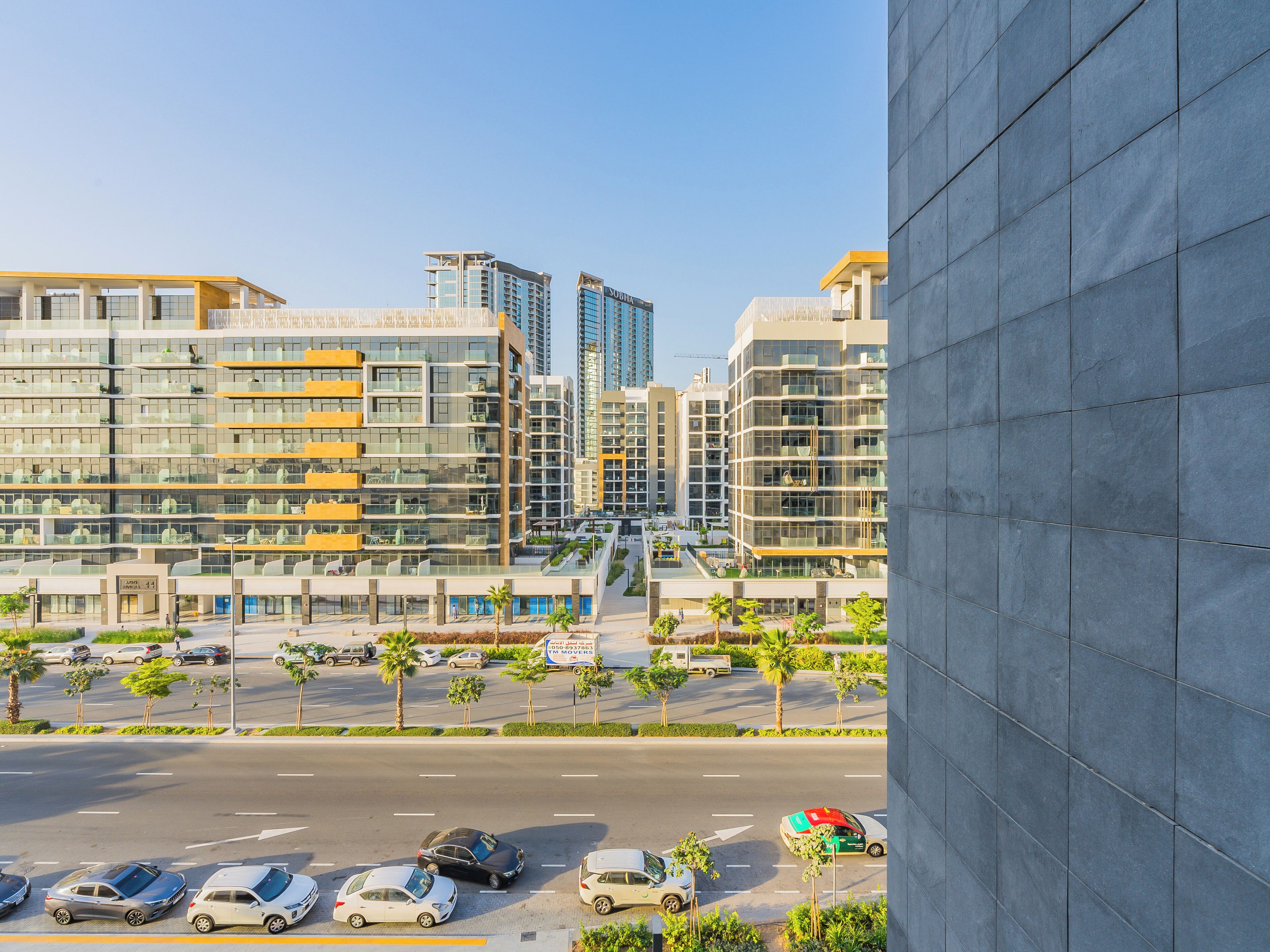 Una zona urbana moderna con edificios altos, un estacionamiento y cielo despejado.