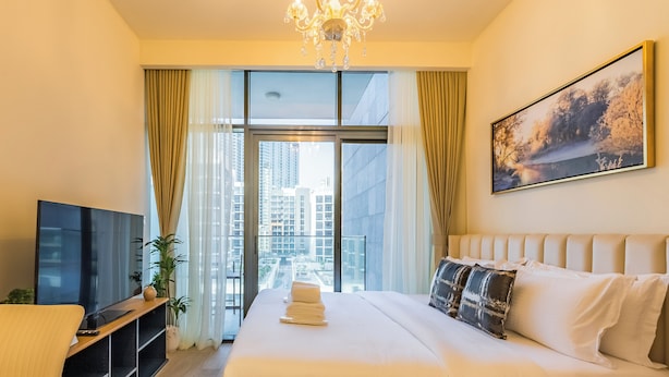 A hotel room with a large bed, a TV, a desk, and a window with curtains. - Tranquil Studio Getaway in Meydan City (Dubai)