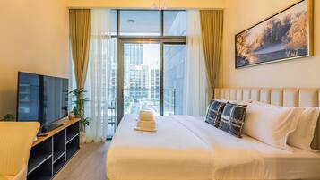 A hotel room with a large bed, a TV, a desk, and a window with curtains.