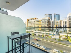Een moderne hotelkamer met balkon, uitzicht op een drukke straat en hoogbouw.