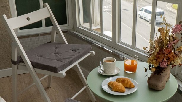 Habitació amb vista al carrer, una taula amb un plat de croissants, una tassa de cafè i un got de suc d'aranja.