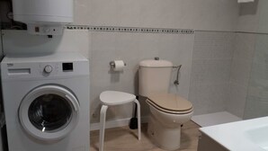 Un bany compacte amb rentadora, vàter i rentaplatets.